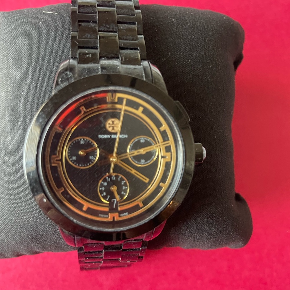 Tory Burch Boyfreind style
Dark shiny metal 
Face accents with gold